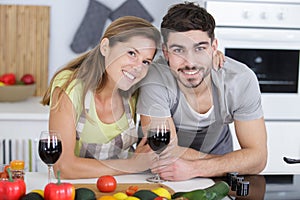 happy couple toasting with wine in kitchen