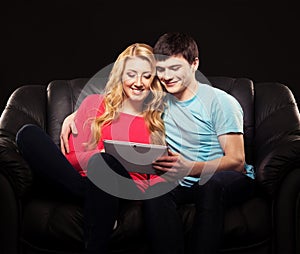 Happy couple together on a sofa with a tablet