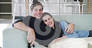 Happy couple, together and watching tv on sofa in living room for bonding, relaxing and peace. Man, woman and married