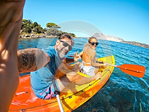 Happy couple of tourist taking selfie inside a kayak canoe in summer holiday travel vacation smiling and having fun at the camera