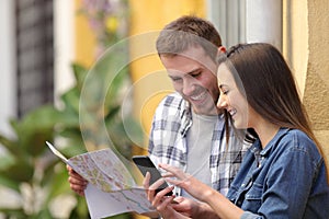 Happy couple of tourists checking phone and map