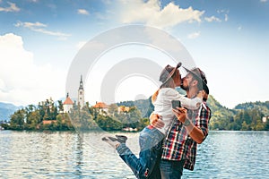 Happy couple of tourists in love is kissing on the background with Bled Lake and Church on the Island, Slovenia. Summer time in