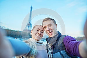 Happy couple of tourists taking selfie near the Eiffel tower