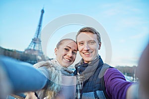 Happy couple of tourists taking selfie near the Eiffel tower in Paris