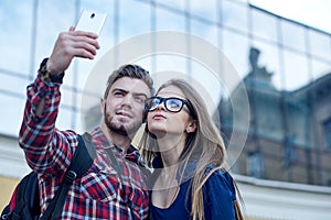 Happy couple of tourists taking selfie in showplace of city