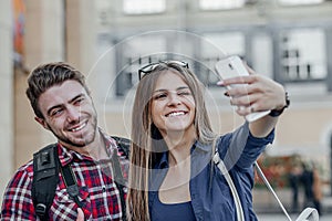 Happy couple of tourists taking selfie in showplace of city