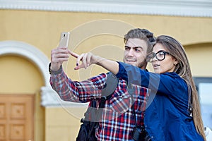 Happy couple of tourists taking selfie in showplace of city. Man and woman making photo on city background