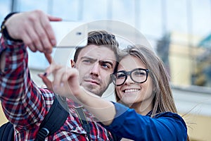 Happy couple of tourists taking selfie in showplace of city. Man and woman making photo on city background