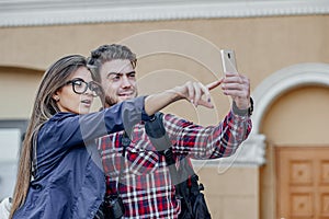 Happy couple of tourists taking selfie in showplace of city. Man and woman making photo on city background photo
