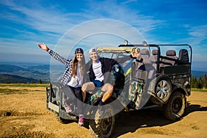 Happy couple travel by car on mountains top.