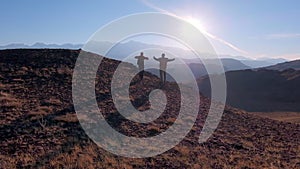 happy couple traveler man woman with backpack climbing up running celebrating success on top mountain at sunset