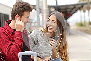 Happy couple of travelers sharing music on holidays