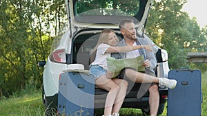 Happy couple traveling by car. Man and woman looking at a road map. Active leisure for the family