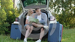 Happy couple traveling by car. Man and woman looking at a road map. Active leisure for the family