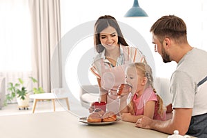 Happy couple treating their daughter with freshly oven baked bun
