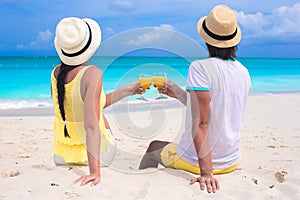 Happy couple with two glasses of orange juice on beach vacation