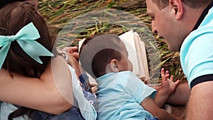 Happy couple with two kids lying on blanket and playing outdoors in slowmo