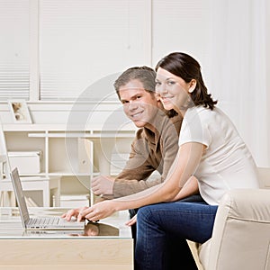 Happy couple typing on laptop