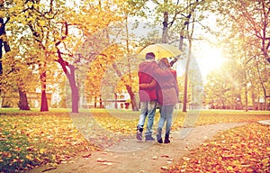 Happy couple with umbrella walking in autumn park