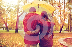 Happy couple with umbrella walking in autumn park