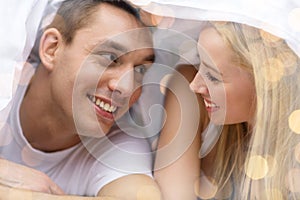 Happy couple under blanket in bed