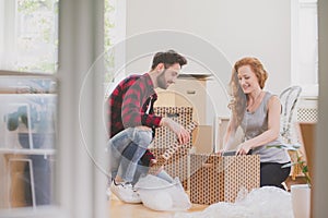 Happy couple unpacking stuff after relocation to new home