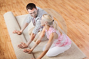 Happy couple unrolling carpet or rug at home