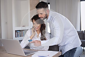 Happy couple using bank card and laptop for shopping online