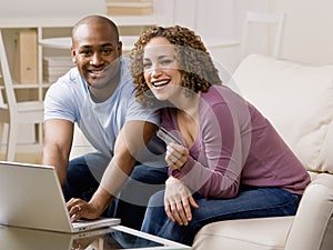 Happy couple using credit card to shop online