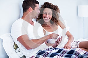 Happy couple using digital tablet on bed