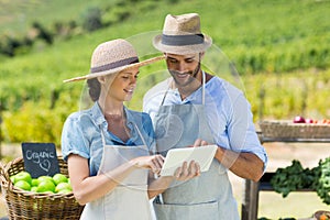 Happy couple using digital tablet at farm