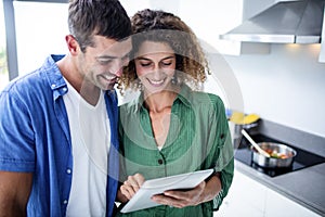 Happy couple using digital tablet in kitchen