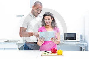 Happy couple using digital tablet in kitchen