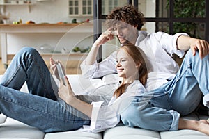 Happy couple using digital tablet while sitting on couch