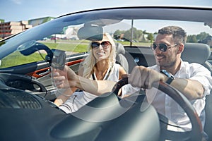 Happy couple using gps navigator in cabriolet car