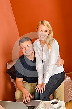 Happy couple using laptop computer sitting together