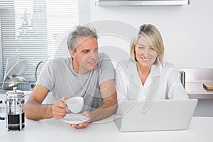 Happy couple using laptop in the morning