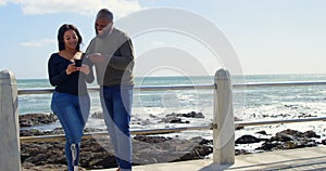 Happy couple using mobile phone near railing on a sunny day 4k