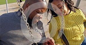 Happy couple using mobile phone in the park on a sunny day 4k