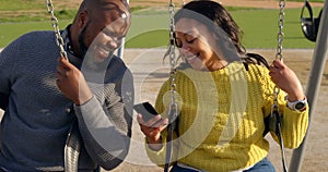 Happy couple using mobile phone in the park on a sunny day 4k