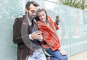 Happy couple using mobile phone for shopping online - Fashion people having fun with smartphone surfing in internet - Trends,