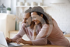 Happy couple using online service on laptop in home kitchen