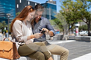 Happy couple using smartphone in city centre