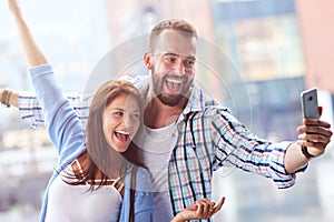 Happy couple using smartphone in city in rainy day