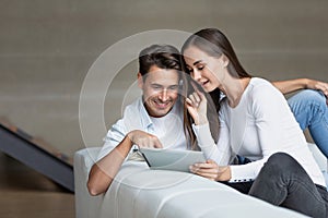 Happy couple using a tablet computer in iving room, choose services online