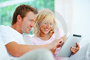 Happy couple using tablet pc. Happy couple sitting on a sofa using tablet pc.