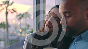 Happy couple on vacation, watch the sunset as woman points outside and man gives her a kiss enjoying their holiday