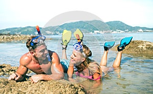 Happy couple of vacationer in love having fun at water on tropical beach in Thailand with snorkel mask and fins - Active youth