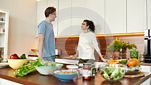 Happy couple, vegetarians talking while going to prepare healthy meal, sandwhich, salad in the kitchen together