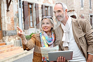 Happy couple visiting old town with tablet in hands